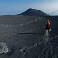 000087 Une randonneuse descend les flancs de l'Etna (Sicile, Italie), recouverts de cendre. Au premier plan, une bombe volcanique. En arrire plan, la silhouette d'un cratre. (Aprs l'ruption de 2002).