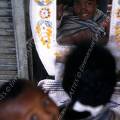 000162 Fillette de douze ans portant son petit frre dans son dos (Antananarivo, Madagascar). La petite fille se reflte dans un miroir sur un march de Tananarive.