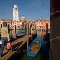 001678 Italienne marchant sur un ponton de bois face au quartier de San Pietro di Castello  Venise (Vntie, Italie). Le campanile que l'on voit ici, ne fait pas corps avec l'glise San Pietro di Castello, ce qui est frquent en Italie et  Venise. Il est de forme carre, fortement pench, au point que l'on ne fait plus sonner ses cloches. C'est le plus beau campanile de pierre blanche de Venise. 