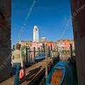 001679 Italienne marchant sur un ponton de bois face au quartier de San Pietro di Castello  Venise (Vntie, Italie). Le campanile que l'on voit ici, ne fait pas corps avec l'glise San Pietro di Castello, ce qui est frquent en Italie et  Venise. Il est de forme carre, fortement pench, au point que l'on ne fait plus sonner ses cloches. C'est le plus beau campanile de pierre blanche de Venise. 