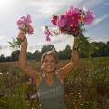 001680 Jeune femme souriante brandissant des bouquets de fleurs champtres (Puy-de-Dme (63), France). Image ralise dans une jachre fleurie cre  l'initiative des fdrations de chasseurs et des agriculteurs locaux. Ce type de jachre en plus d'amliorer les paysages, favorise la biodiversit et offre un refuge et des sources de nourriture  une faune varie.
