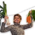 001689 Femme joyeuse et souriante brandissant des carottes et des poireaux issus de l'agriculture biologique.