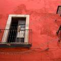 001715 Fentre ouverte se dtachant sur un mur crpi rouge. Devant la fentre, un petit balcon entour d'une balustrade en fer, sur laquelle prend appui un balai abandonn. De nombreux fils lectiques courent sur le mur (Guanajuato, Mexique).